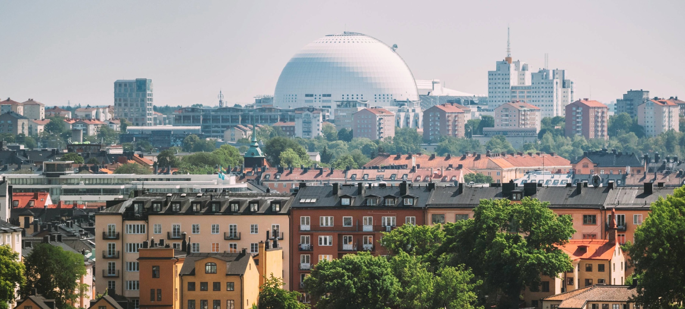 Bild över färggranna husfasader, grönska och i mitten av bild Globen, i Stockholm.