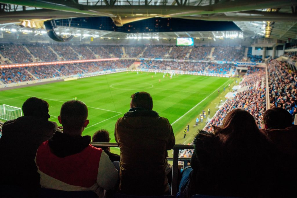 Ett publikhav på läktaren framför en fotbollsplan under en fotbollsmatch.