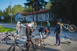 Några unga vuxna/ungdomar som meckar med cyklar, del av aktivitet arrangerat av Miljöverkstan Flaten, Äventyrsgruppen som anordnar gratis aktiviteter med fokus på friluftsliv för asylsökande och nya personer i Sverige.