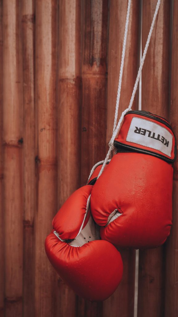 Ett par röda boxningshandskar som hänger mot en vägg.