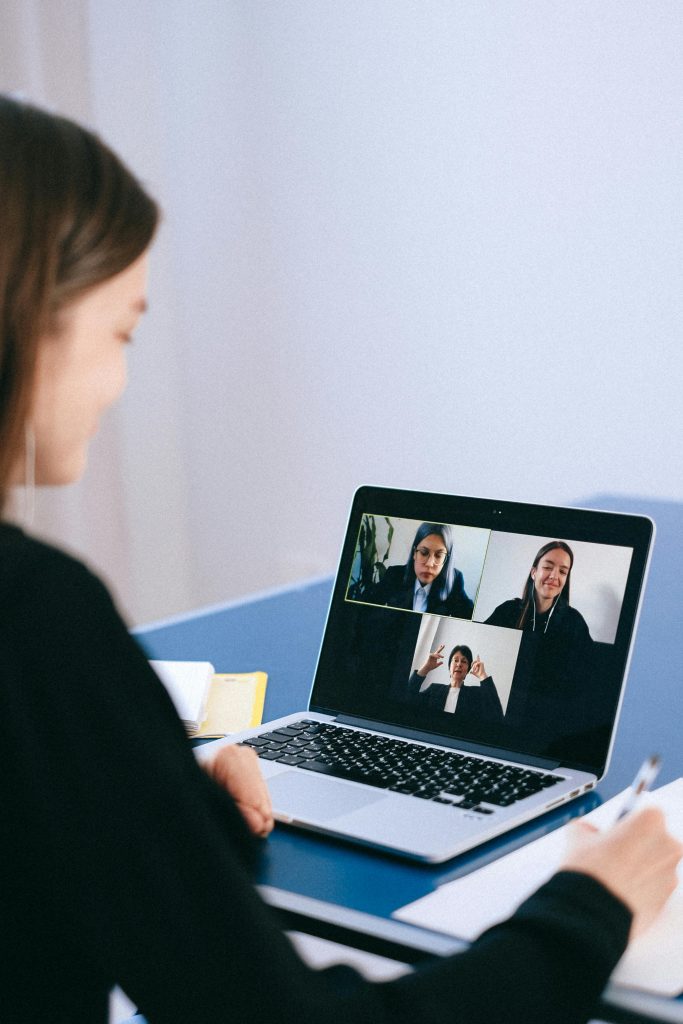 En kvinna sitter med sin laptop och har ett digitalt möte tillsammans med tre andra kvinnor som syns i skärmen.
